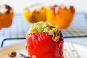Stuffed red pepper in the front center with yellow peppers in the background.