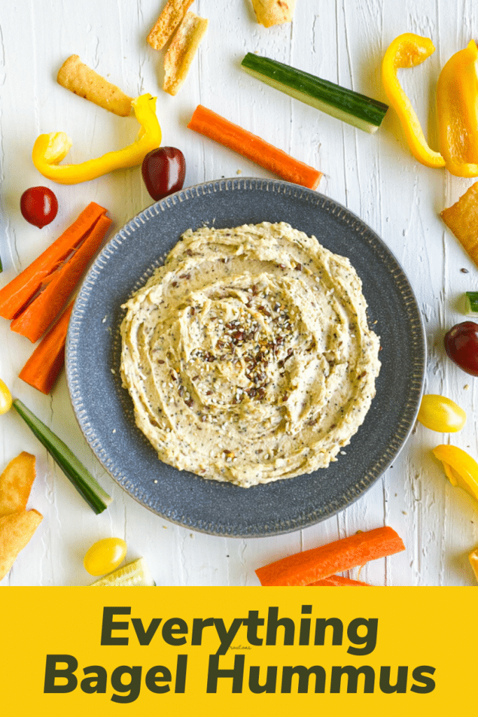 Everything bagel hummus in center. top down view. Raw veggies surrounding it. bottom part title of post with yellow background. 