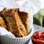 Air fryer zucchini fries in basket with side of marinara sauce